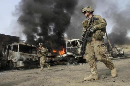 NATO troops walk near burning NATO supply trucks after, what police officials say, was an attack by militants in the Torkham area